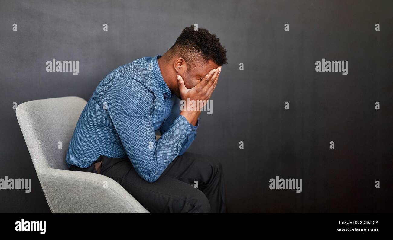 African business man with hands in front of face for despair Stock Photo