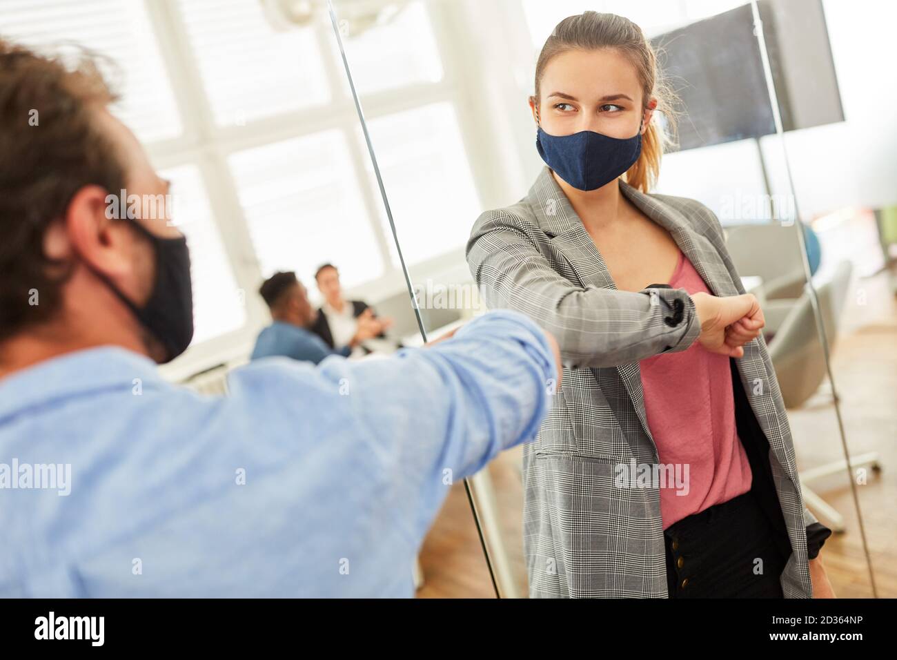 Business people with everyday masks greet each other with elbows because of Covid-19 Stock Photo