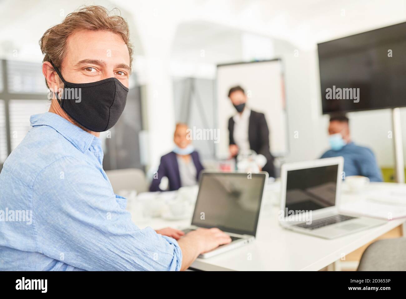 Business man with face mask works or researches on laptop computer Stock Photo