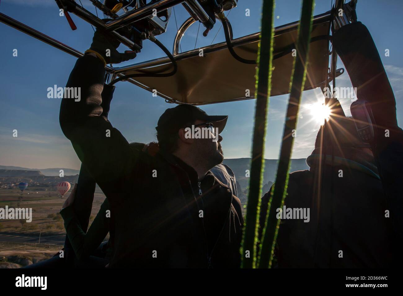 A hot air balloon pilot navigates his balloon through the sky near Goreme in the Cappadocia region of Turkey. Stock Photo