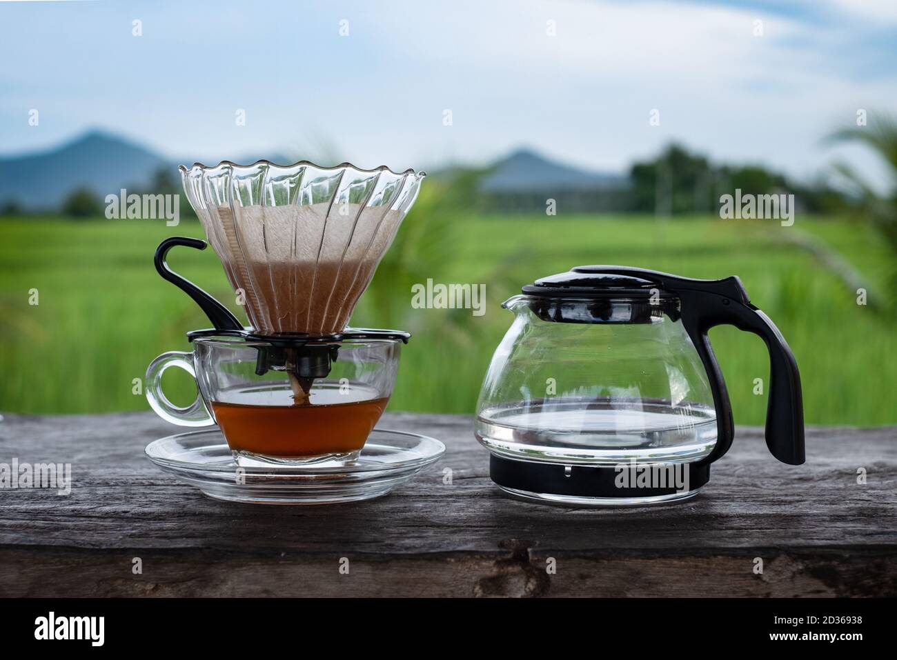 Coffee glass cup and water pot on the wood table at blue sky background