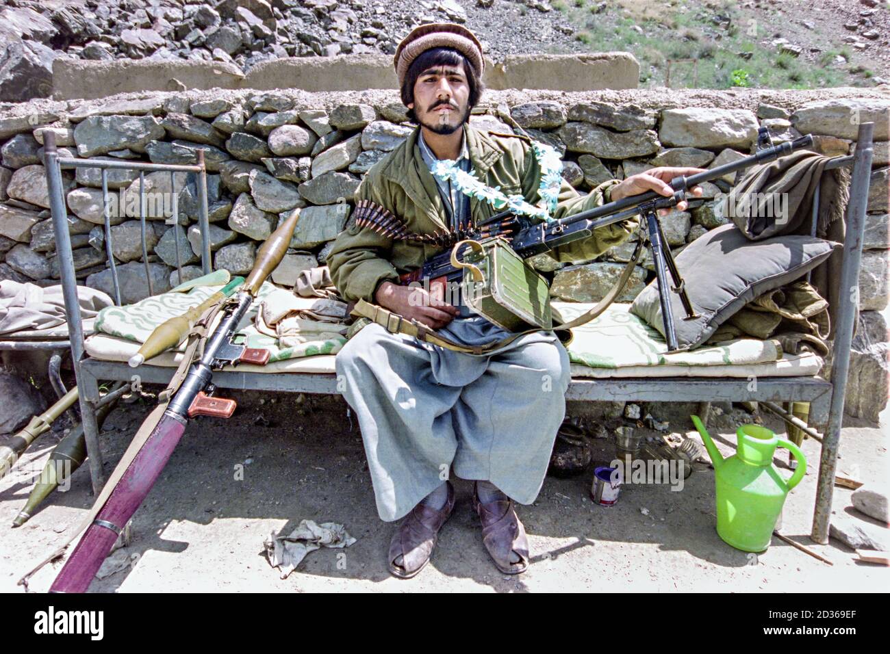 An Afghan mujahideen guerrilla fighter poses with his Soviet made PK machine gun and an RPG launcher at a rebel base during the Afghan Civil War May 11, 1989 in the Paghman Valley, Afghanistan. Stock Photo