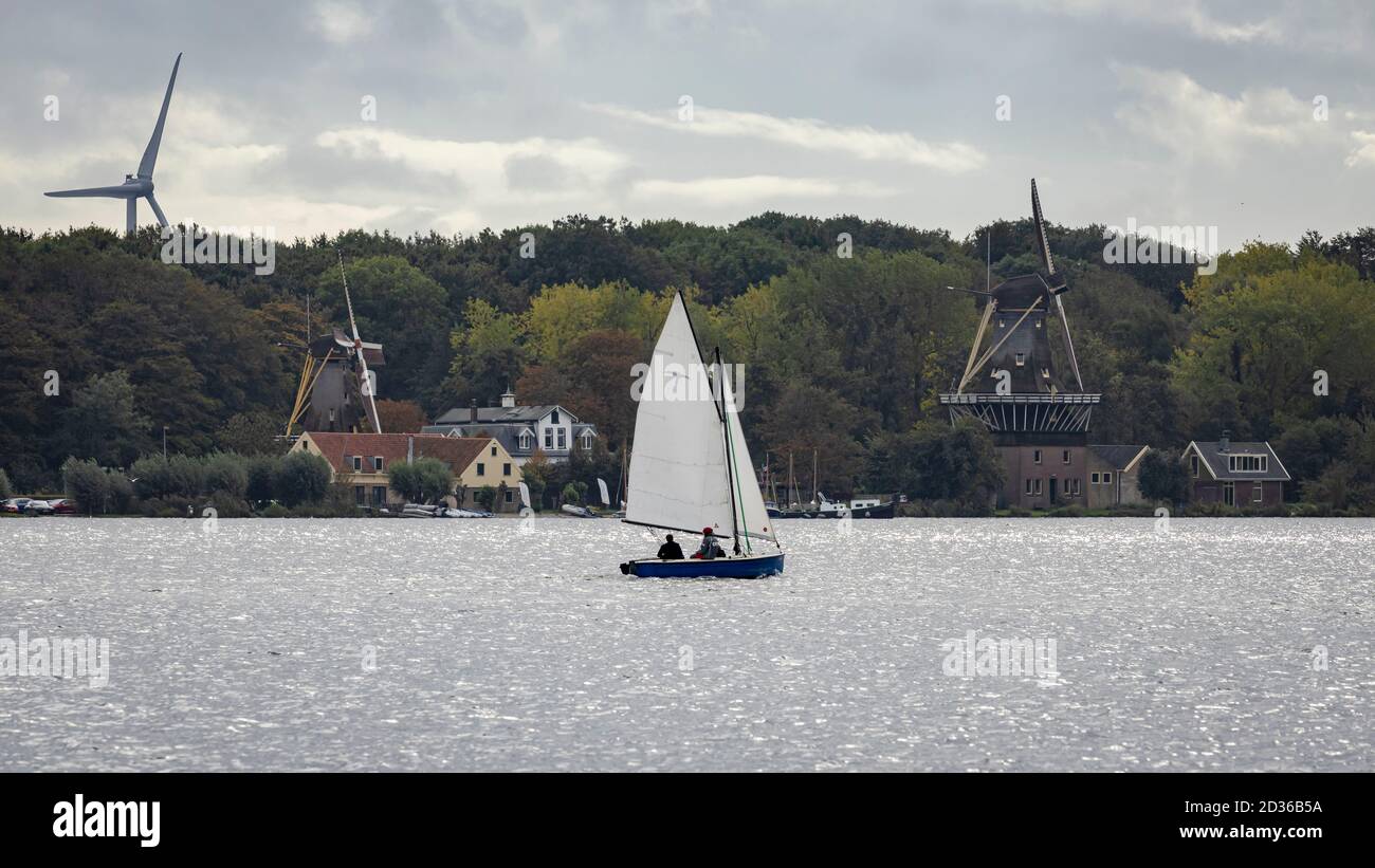 Sailboat in front of historic and modern windmills Stock Photo