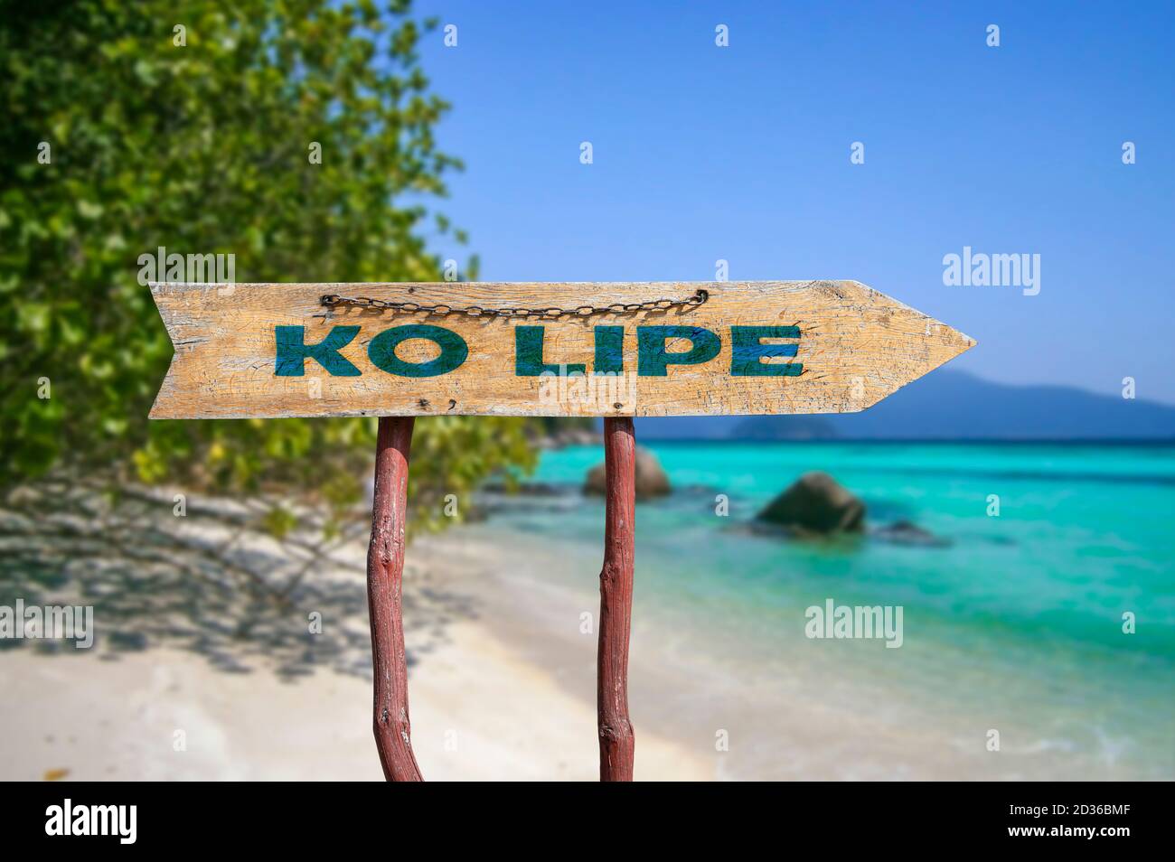 Ko Lipe wooden arrow road sign against tropical beach with white sand and turquoise water background. Travel and relaxation concept. Stock Photo