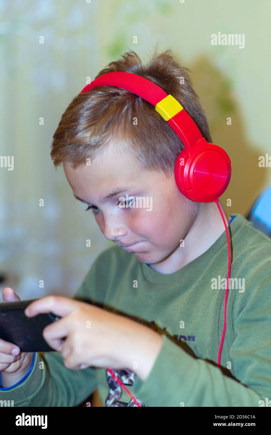 Close up side view school boy 9s calm surprised Face on Smart phone watching movie or feelings in the his game at home Stock Photo