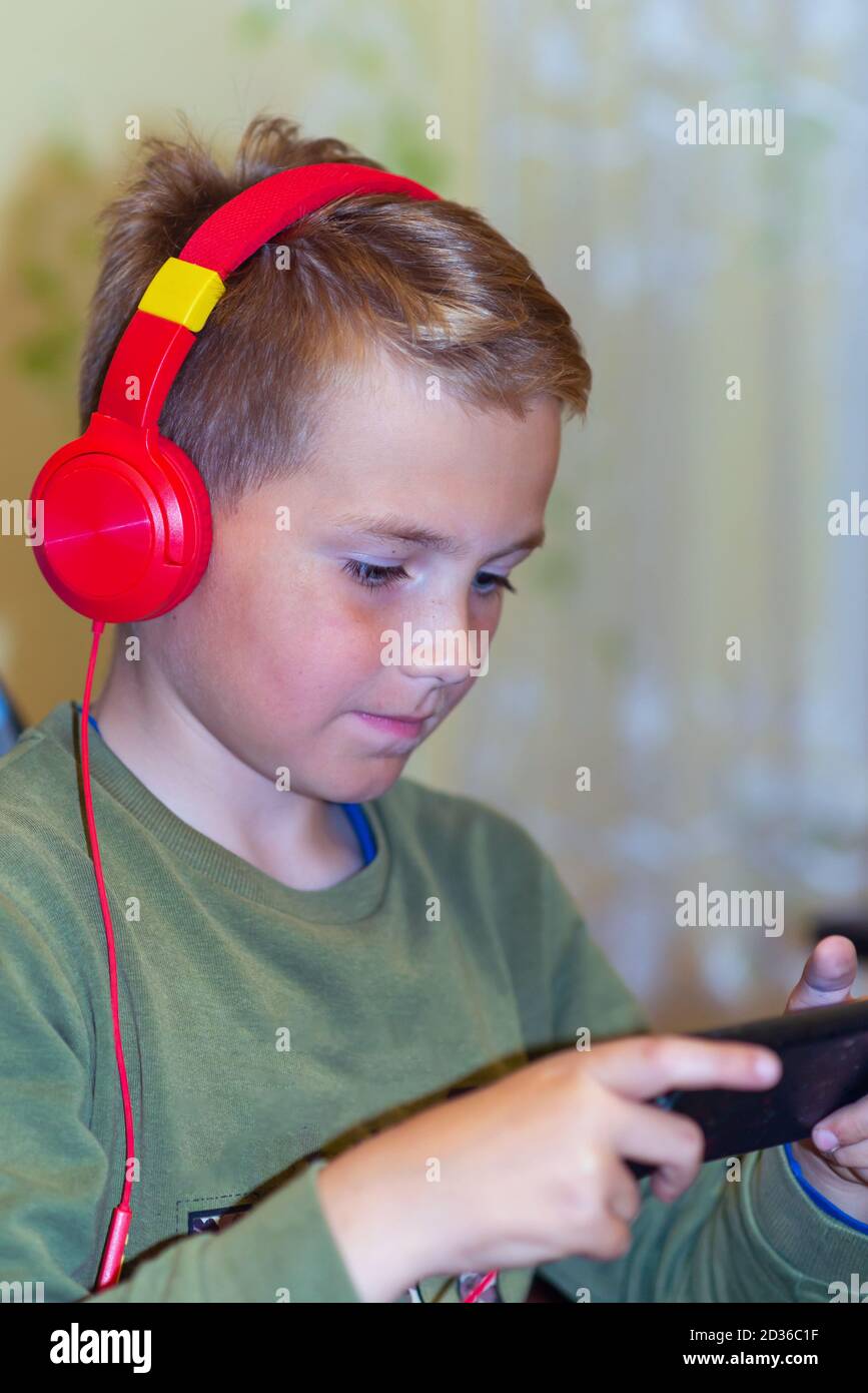 Close up side view school boy 9s calm surprised Face on Smart phone watching movie or feelings in the his game at home Stock Photo