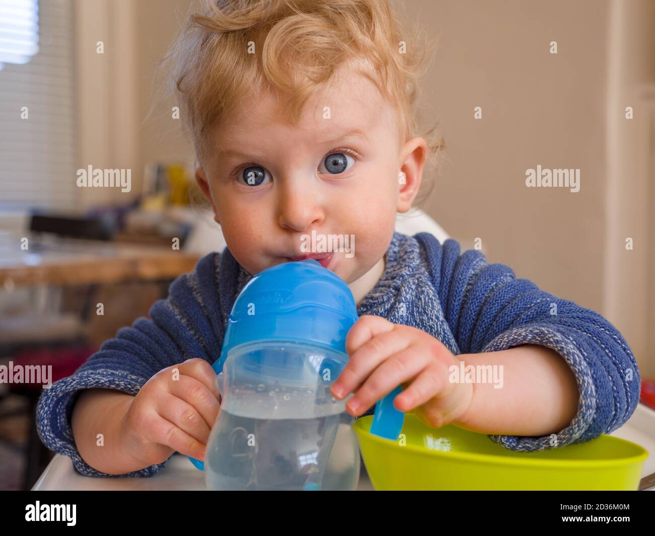 One year old baby boy drinking water while eating Stock Photo