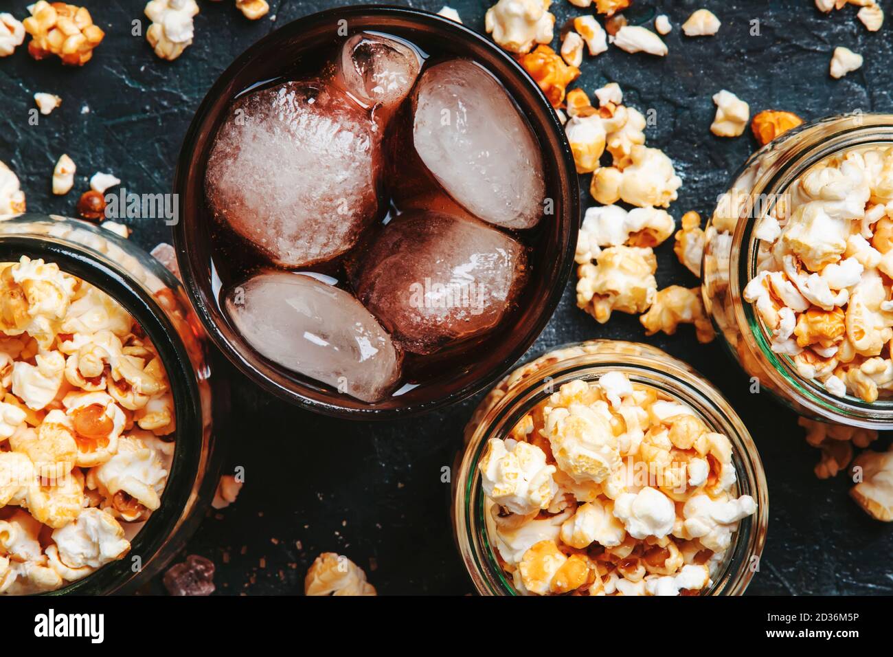 Ice cola and caramel popcorn, unhealthy food and drink, black table