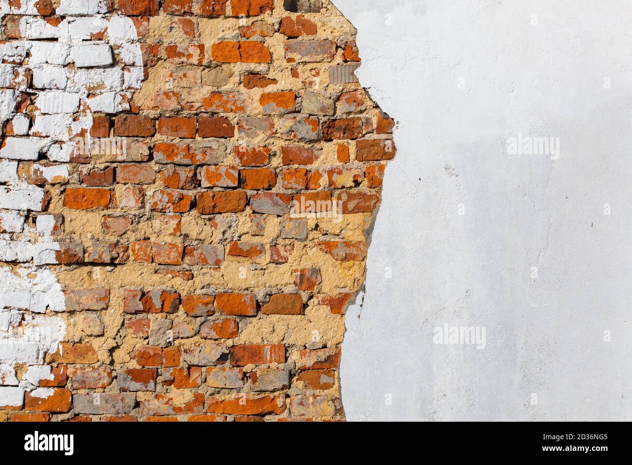 old bad brick wall with leftovers of white peeled thick plaster Stock Photo