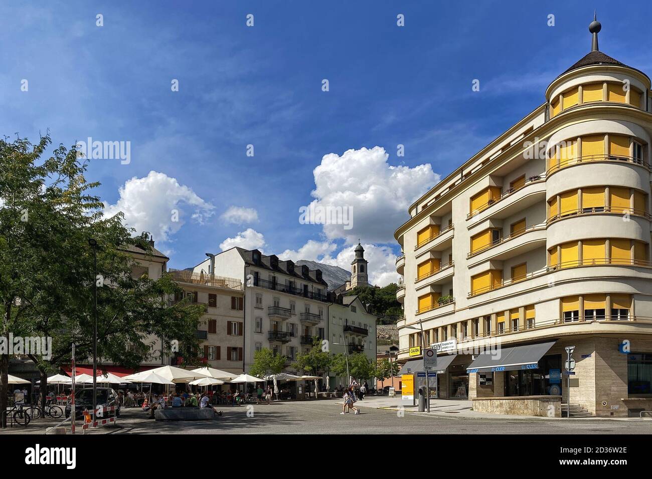 Sion, Switzerland, July 25: Citizens and visitors to the city relax in the shade of trees and on the terraces of cafes in one of the city squares on a Stock Photo