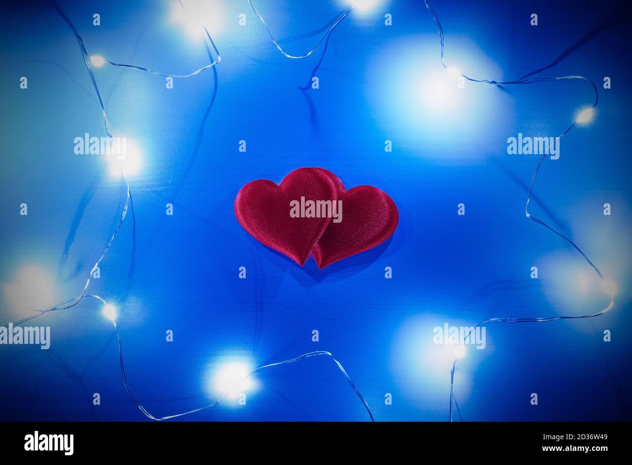 Two red hearts and garland around on wooden background. Valentine's day concept. Stock Photo