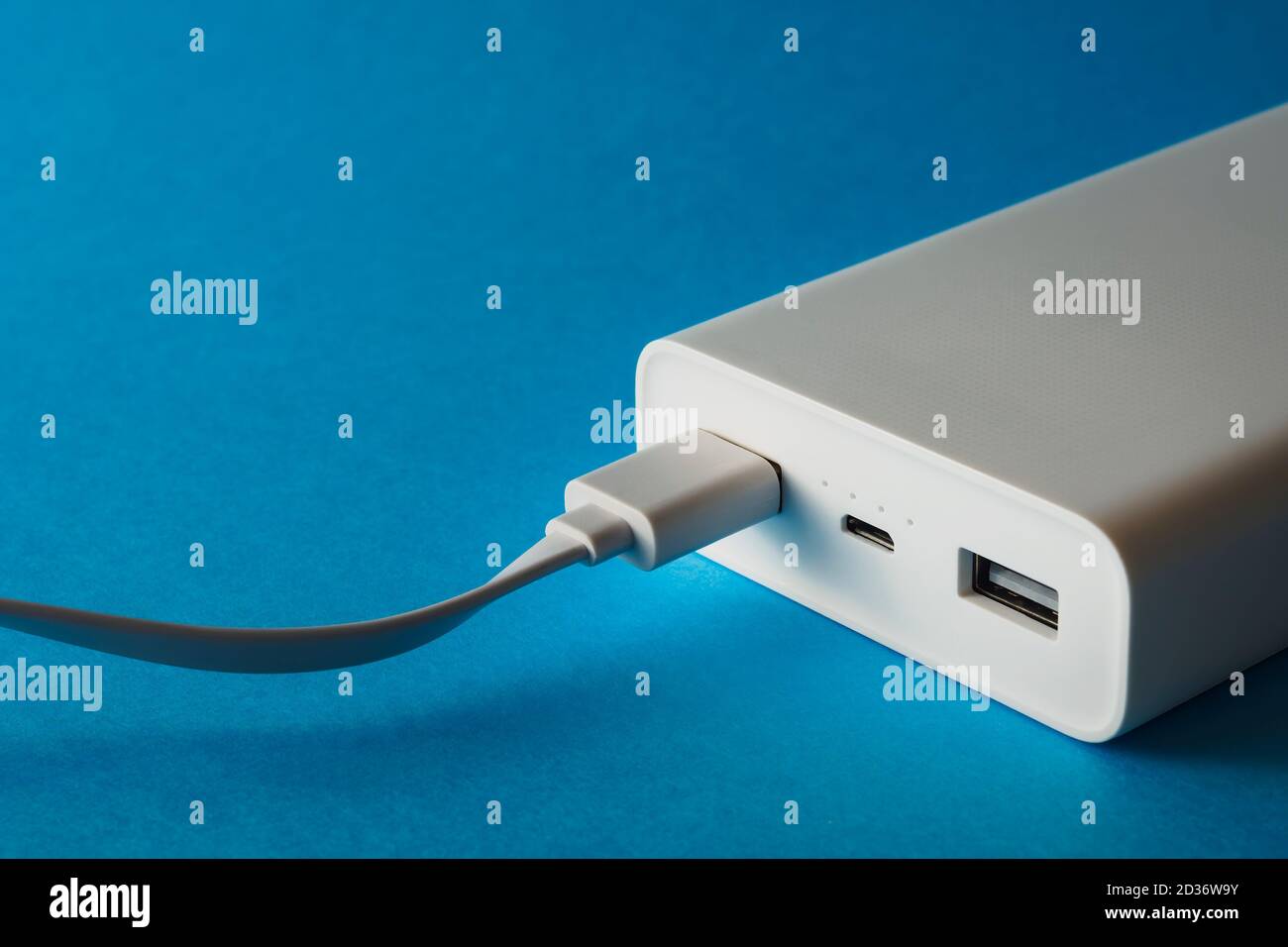 Power bank and cable in usb port on blue background, selective focus Stock Photo