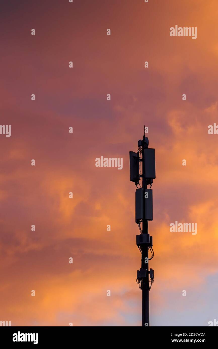 Cellular communications tower on beautiful dramatic clouds background in evening, vertical view Stock Photo