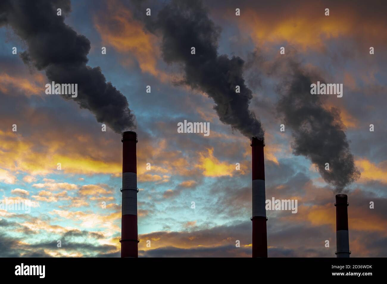Three smoked pipes on dramatic colorful sky background. Air pollution concept Stock Photo