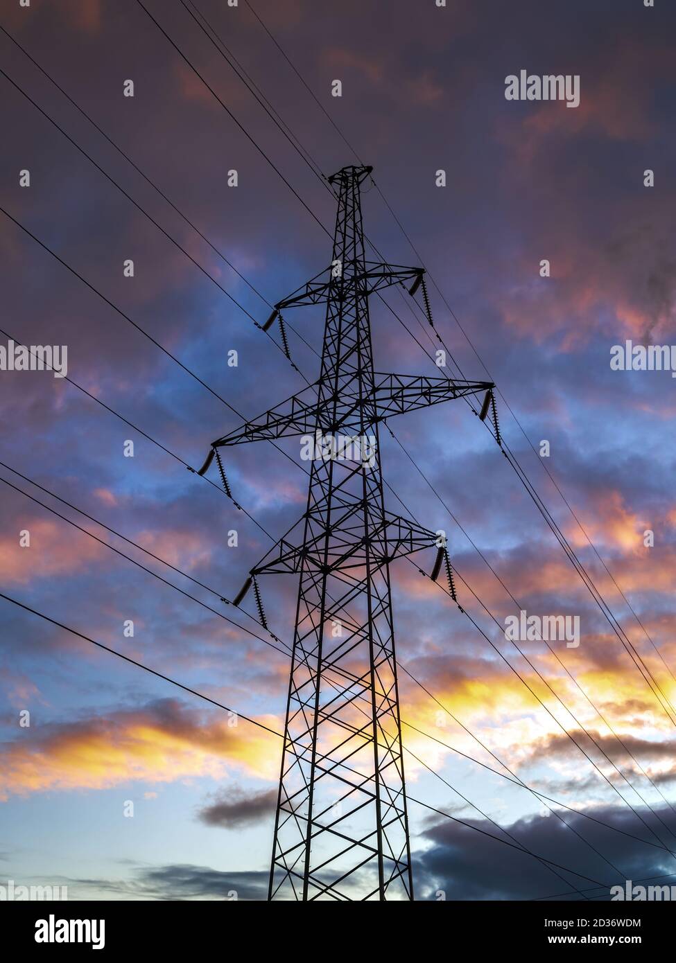 Transmission tower, power tower on dramatic colorful sky background. Steel lattice tower, used to support an overhead power line, vertical view Stock Photo