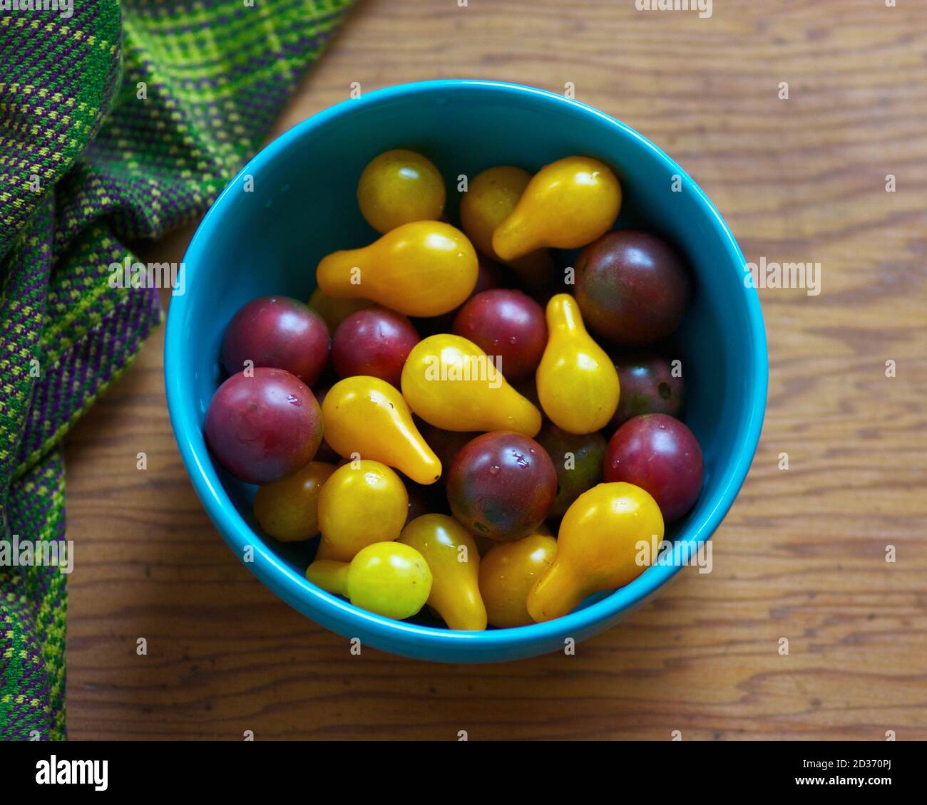Bowl of fresh yellow and purple cherry tomatoes. Stock Photo