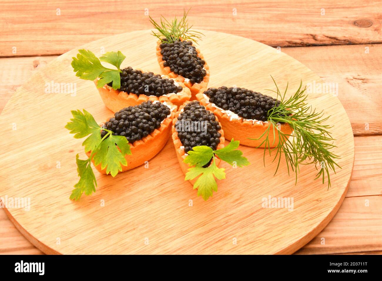 Tartlets with black caviar and fresh greens Stock Photo