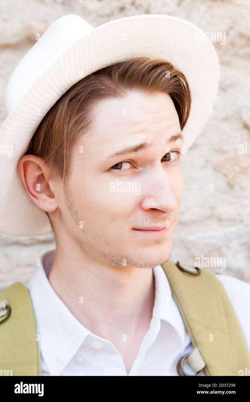 Young caucasian man wearing a white hat smiles at the camera. Close-up Stock Photo