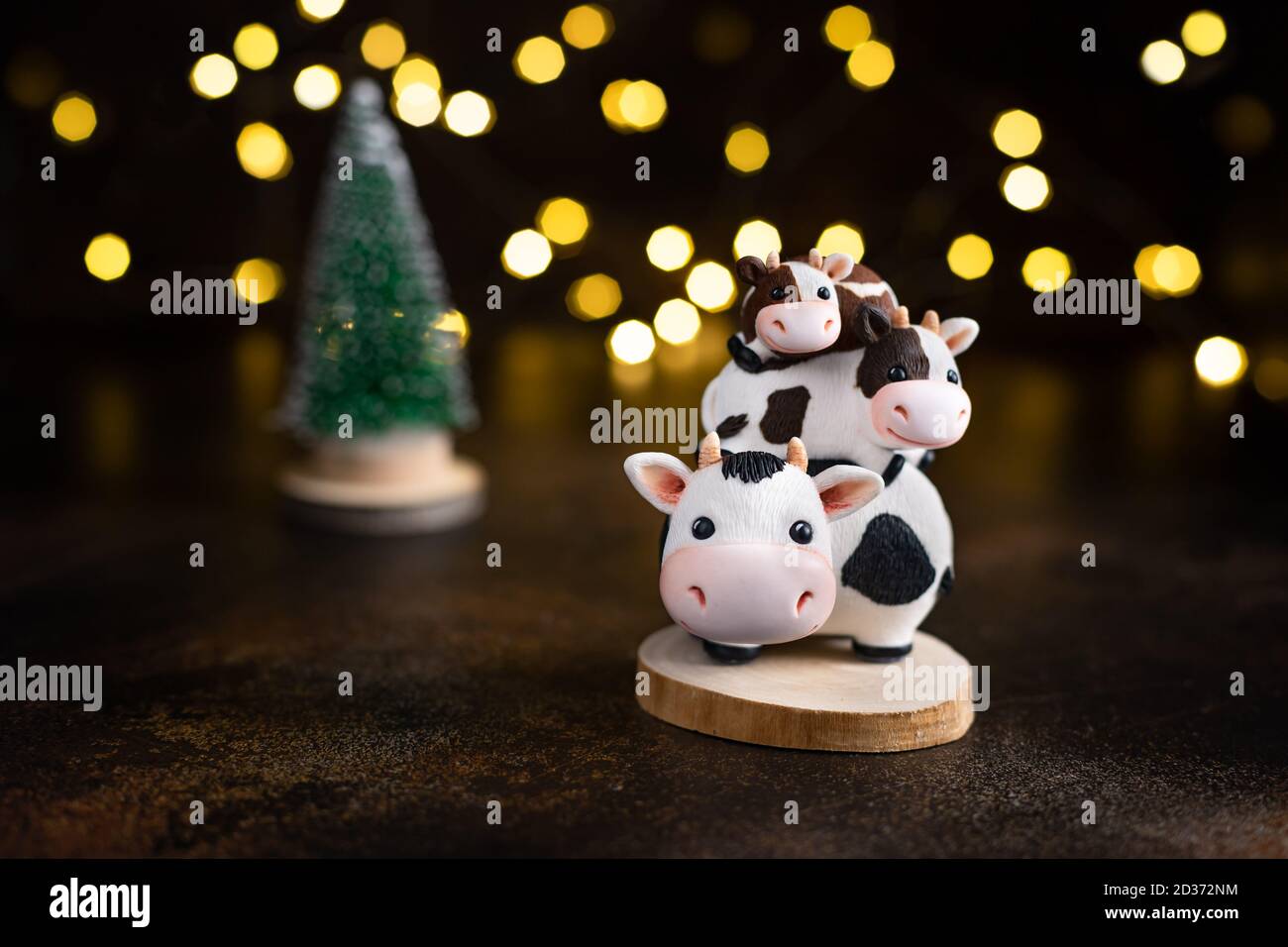 family of bulls on the background of a Christmas tree and Christmas lights. Stock Photo