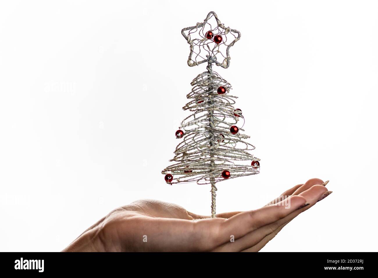 Hand holding small silver wire Christmas tree isolated on white
