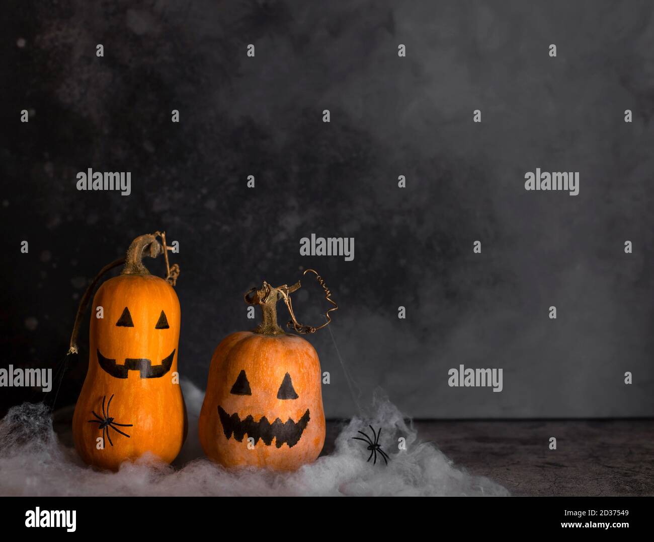 Halloween pumpkins with painted faces and a spider web with crawling spiders. Stock Photo