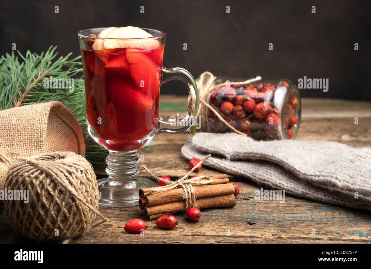 Christmas background with a glass of mulled wine, knitted socks and fir branches on a wooden background. Stock Photo