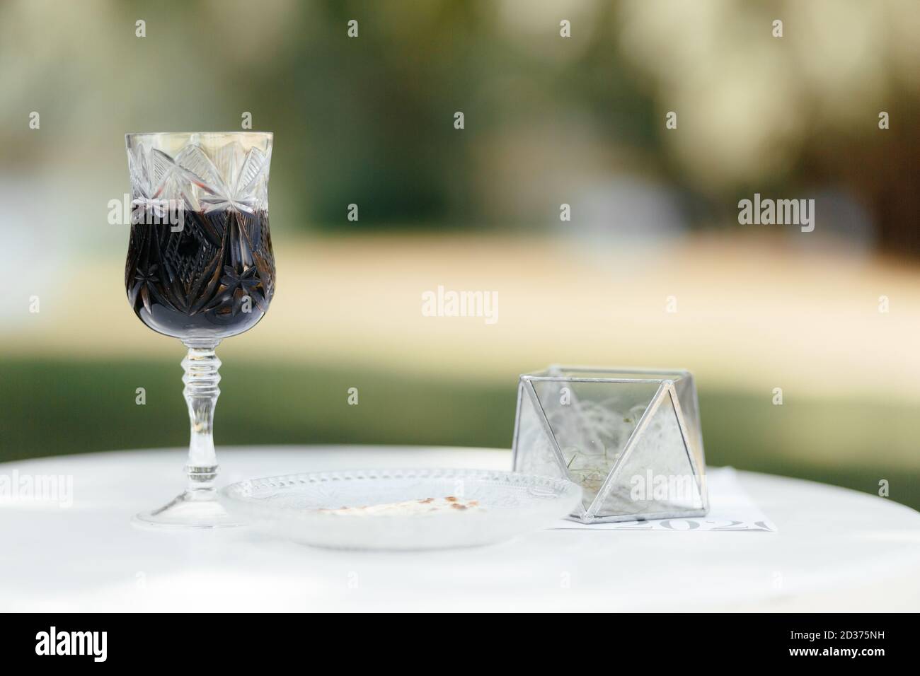 Glass of red wine on the white tablecloth at the blurred background with the place for your text. Wine background. Stock Photo