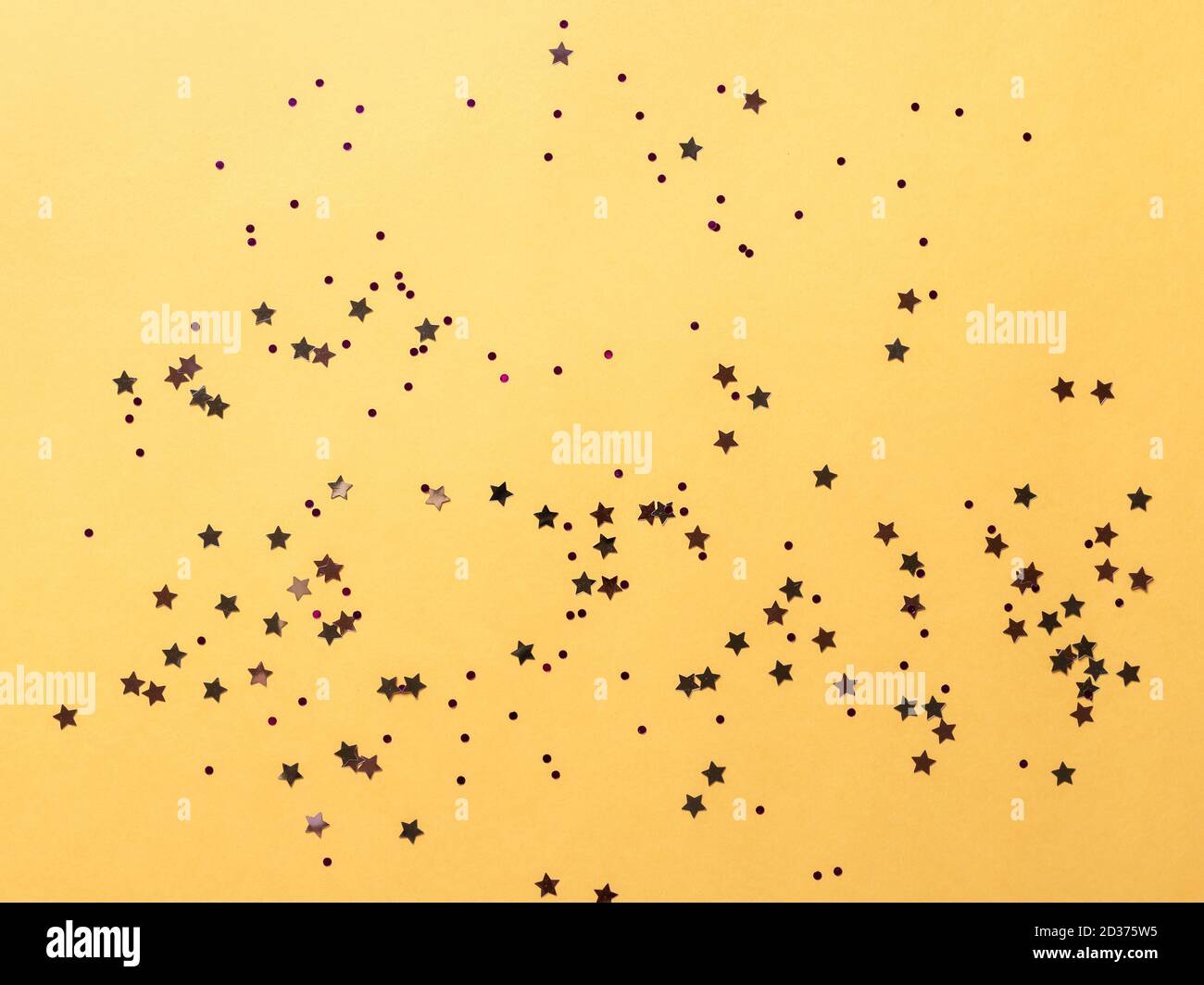 flat lay of shining round, star sparkle on yellow paper background ...