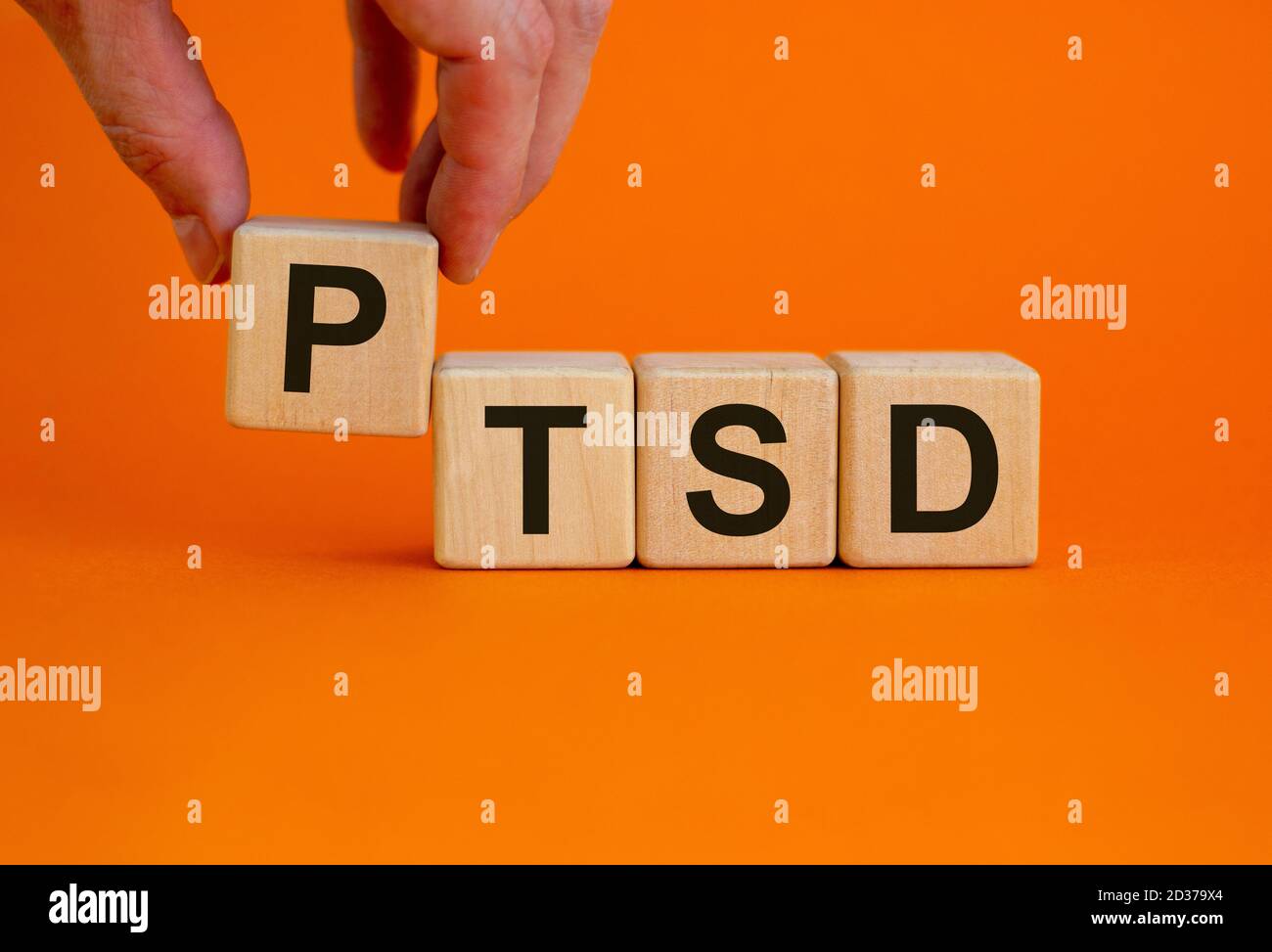 Concept words 'PTSD, post-traumatic stress disorder' on cubes on a beautiful orange background. Male hand. Copy space. Stock Photo
