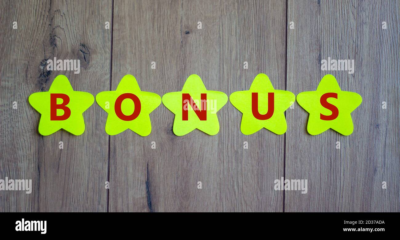 Concept word 'bonus' on golden paper stars on a beautiful wooden