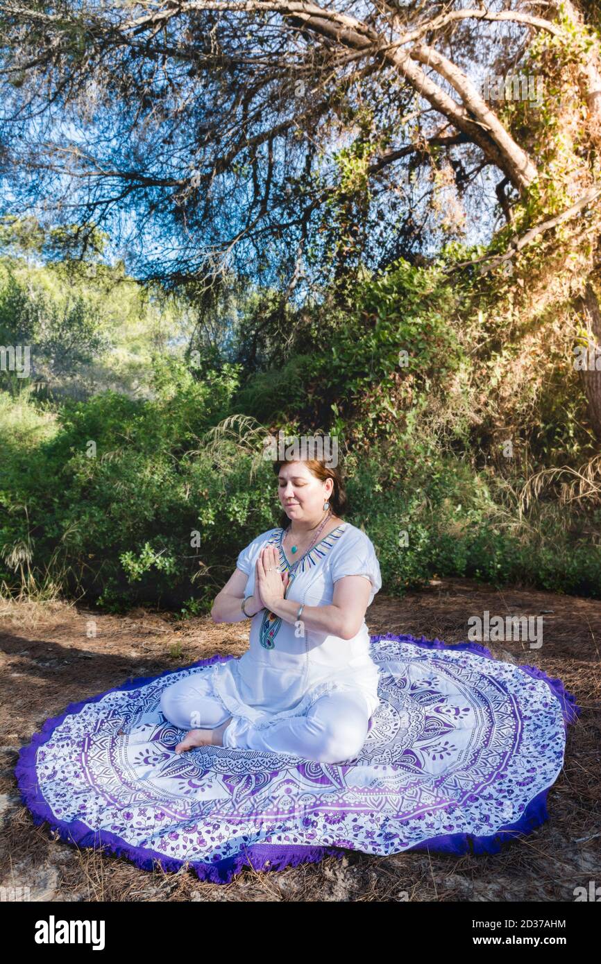 Woman meditating sitting in the lotus position with her hands in front ...
