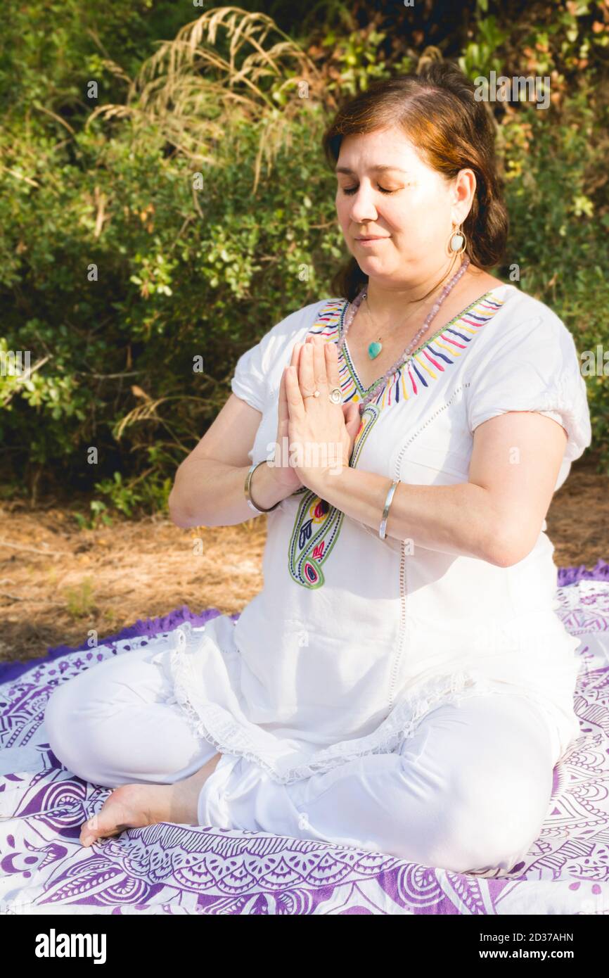 Woman meditating sitting in the lotus position with her hands in front ...