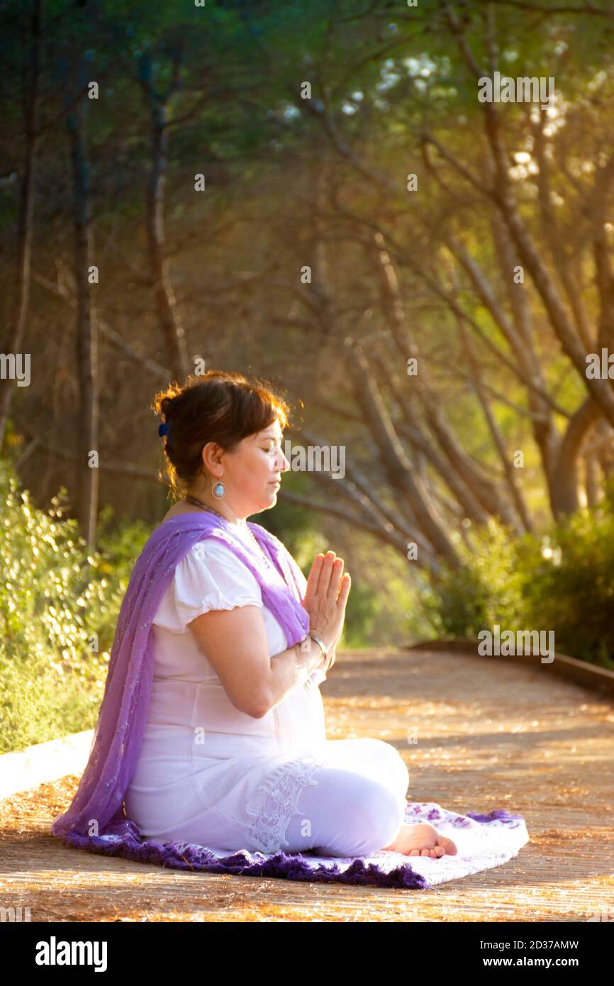 Woman meditating sitting in the lotus pose with her hands in front of ...