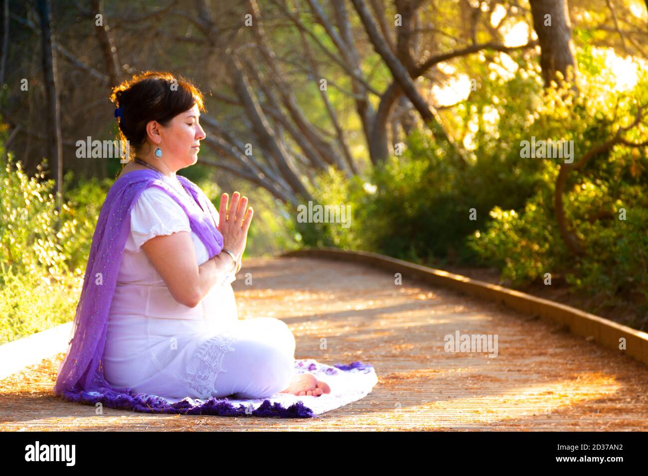 Woman meditating sitting in the lotus pose with her hands in front of ...