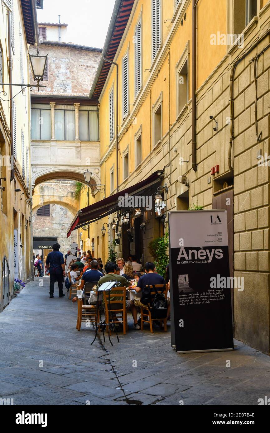 Tourists having lunch in an outdoor restaurant in Via di Beccheria, historic centre of Siena, Unesco World Heritage Site, Tuscany, Italy Stock Photo