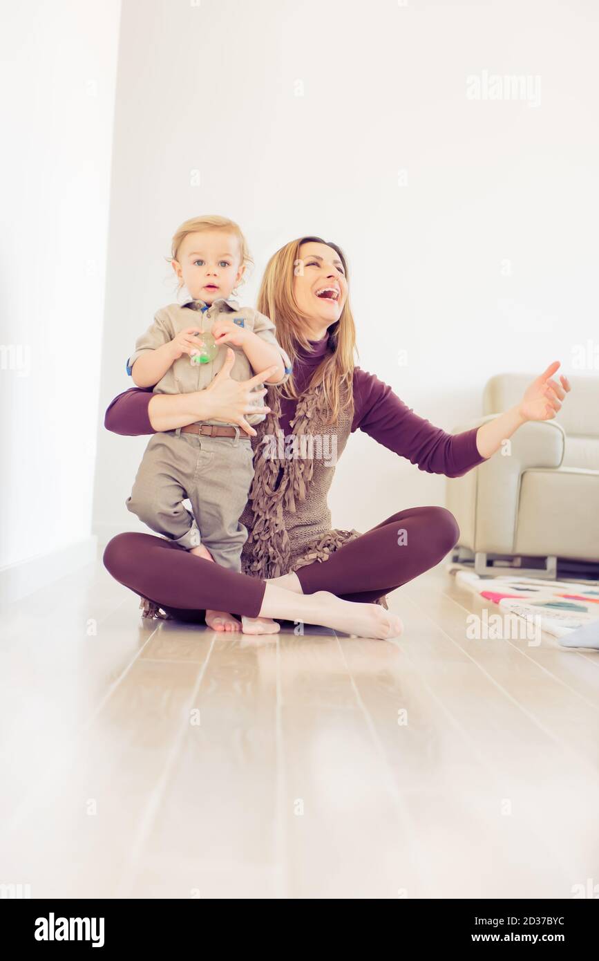 Happy mother sitting on the floor with her baby boy and smiling Stock ...