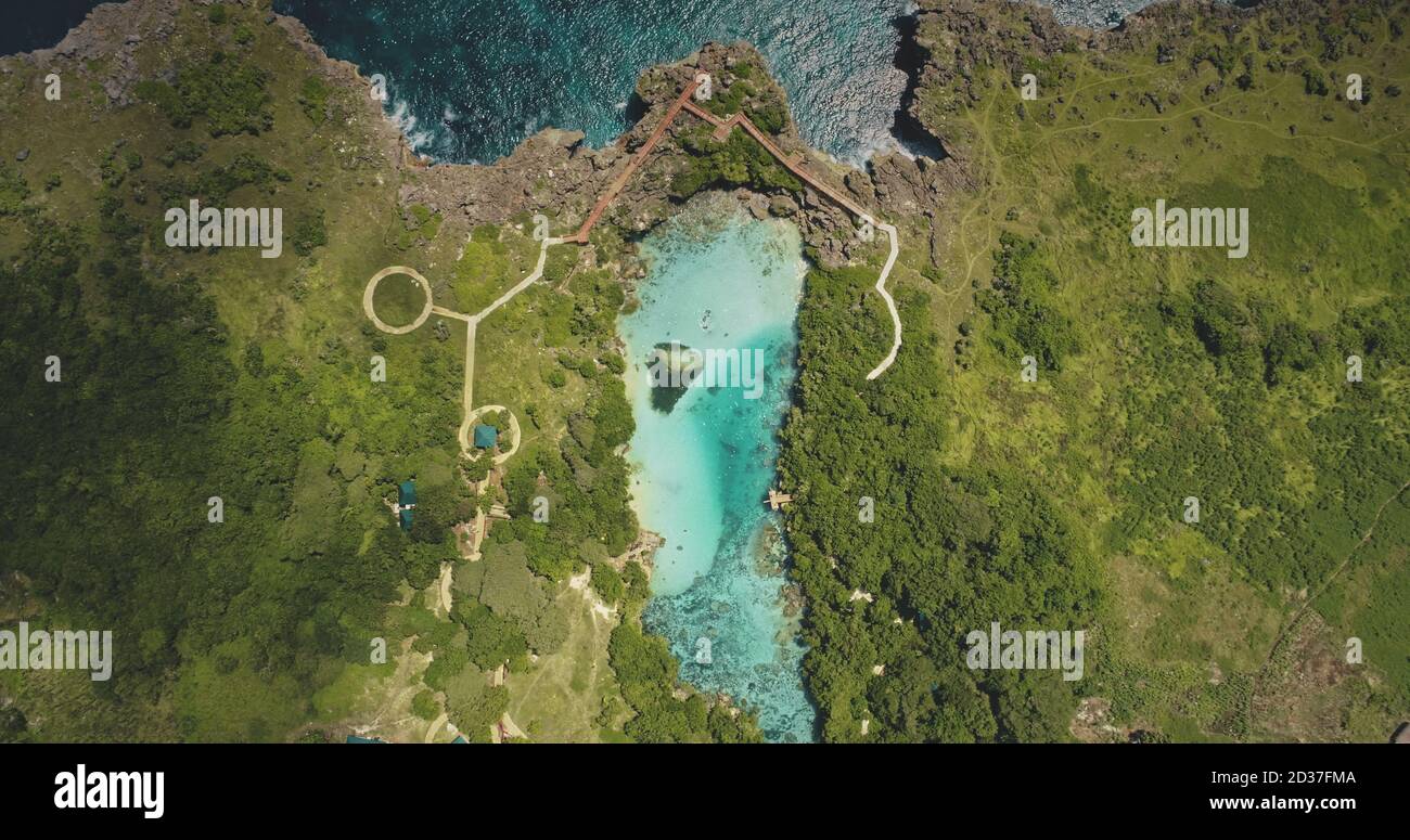 Top down of designed path at azure lake on green cliff sea shore aerial view. Greenery tropical meadow with trees, grasses on ocean coast. Epic landscape of Weekuri landmark, Sumba Island, Indonesia Stock Photo