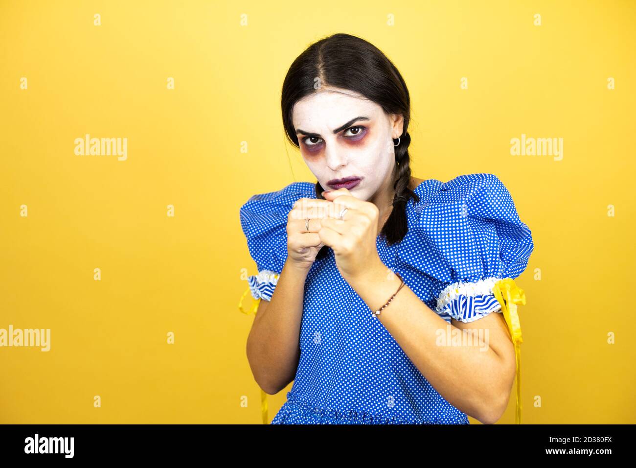 woman wearing a scary doll halloween costume over yellow background