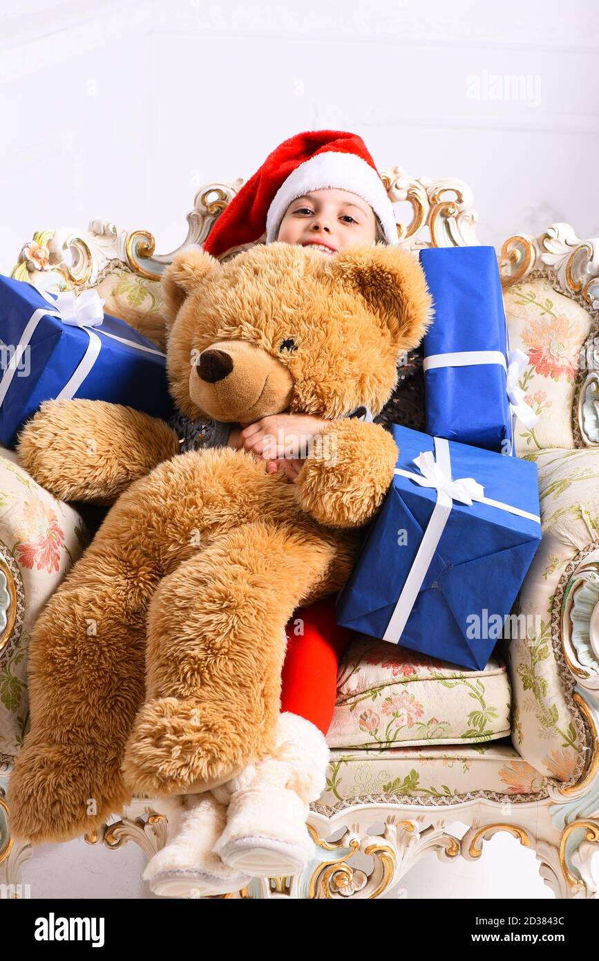 Miss Santa in red hat sits on chic arm chair and holds gift boxes and ...