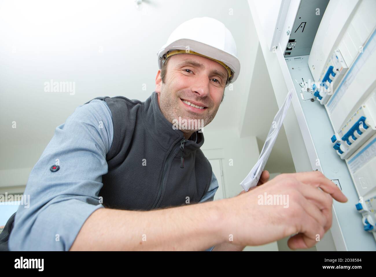 electrician posing and smiling next to a panel Stock Photo