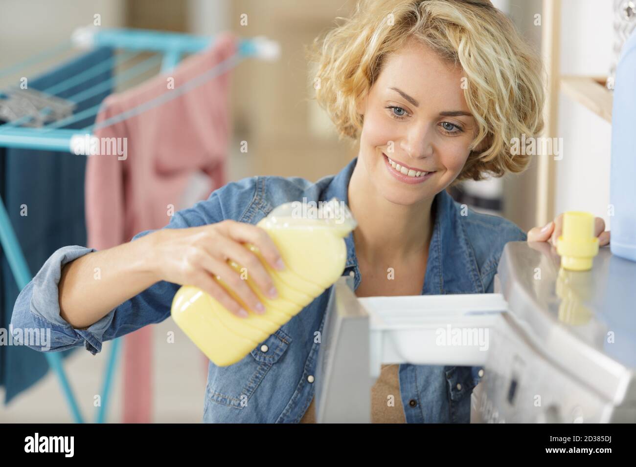 woman pouring fabric conditioner into washing machine drawer Stock Photo