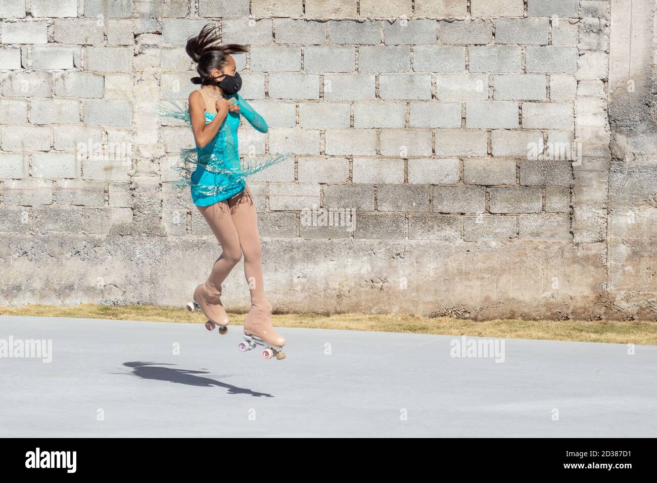 Teenage girl wearing a mask and performing a jump on roller skates