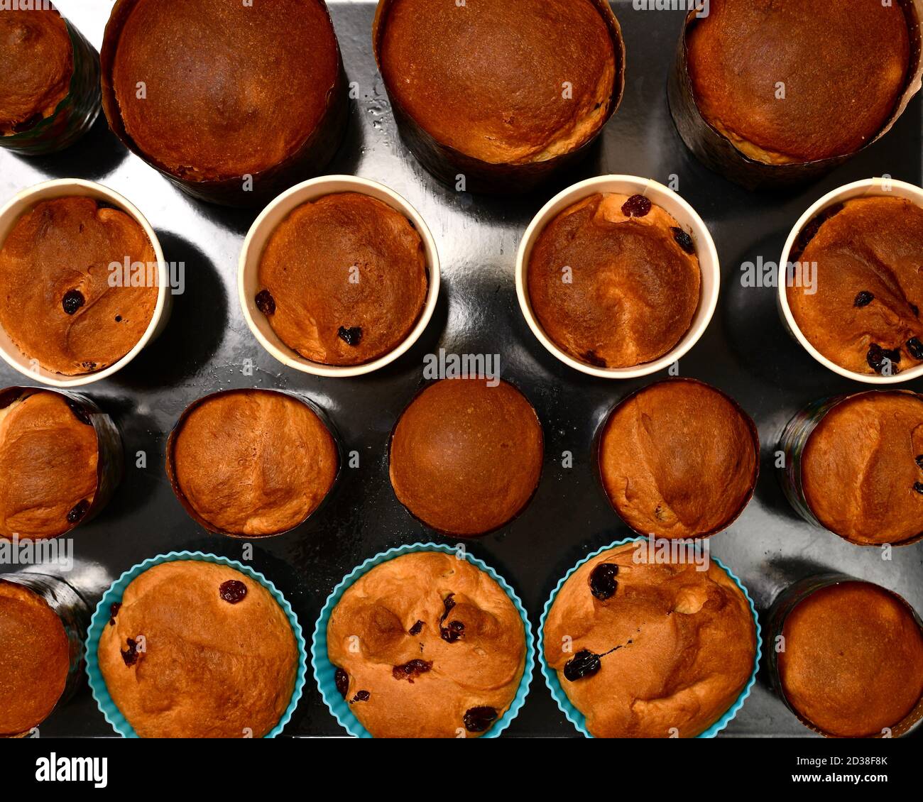 A background of baked ruddy Easter cakes, in round baking tins, on a black oven baking sheet. Stock Photo