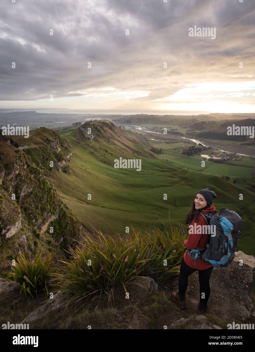 Young woman with backpack posing at the top of a mountain. Te Mata Peak, Hawke's Bay, New Zealand. Stock Photo
