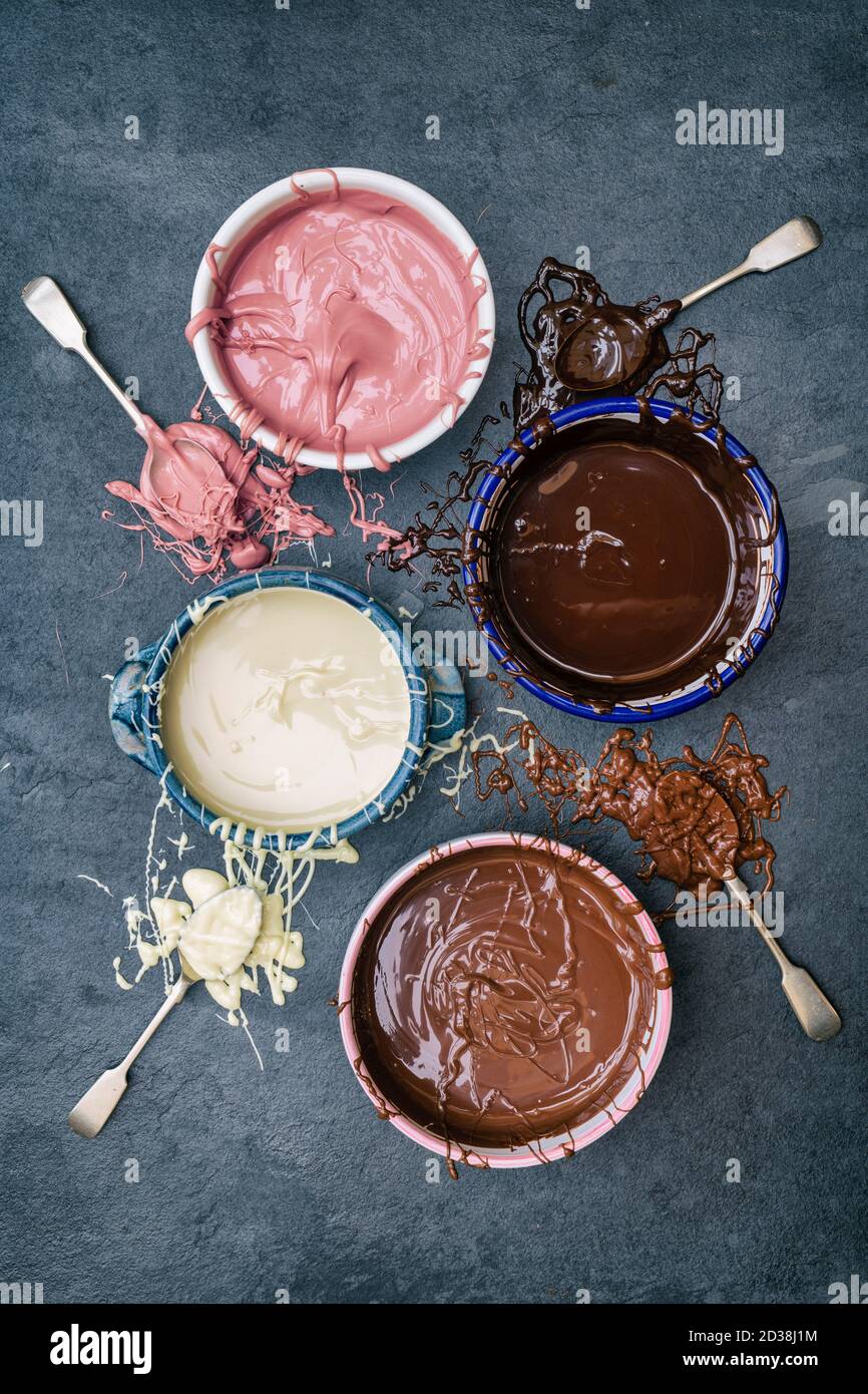 Four types of melted chocolate in bowls. Dark chocolate, milk chocolate