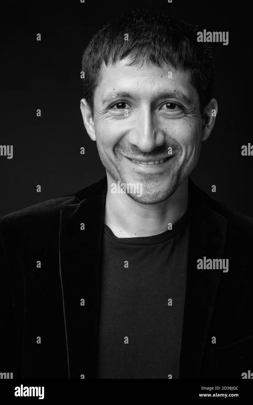 Portrait of Hispanic businessman in suit against black background Stock Photo