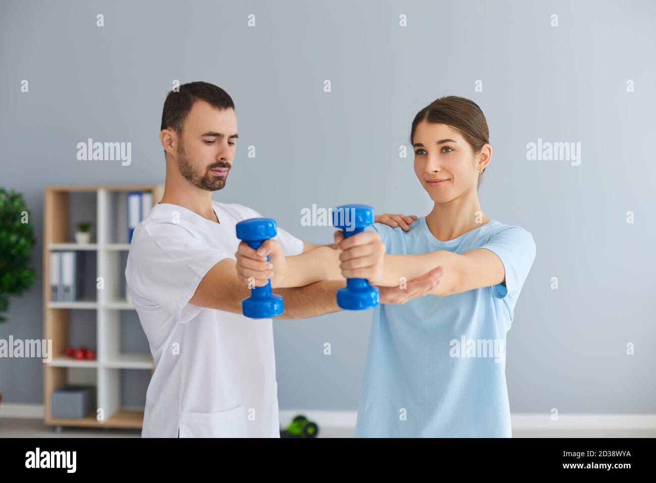 Chiropractor or osteopath fixing woman patient with dumbbels in right position for pain relief Stock Photo
