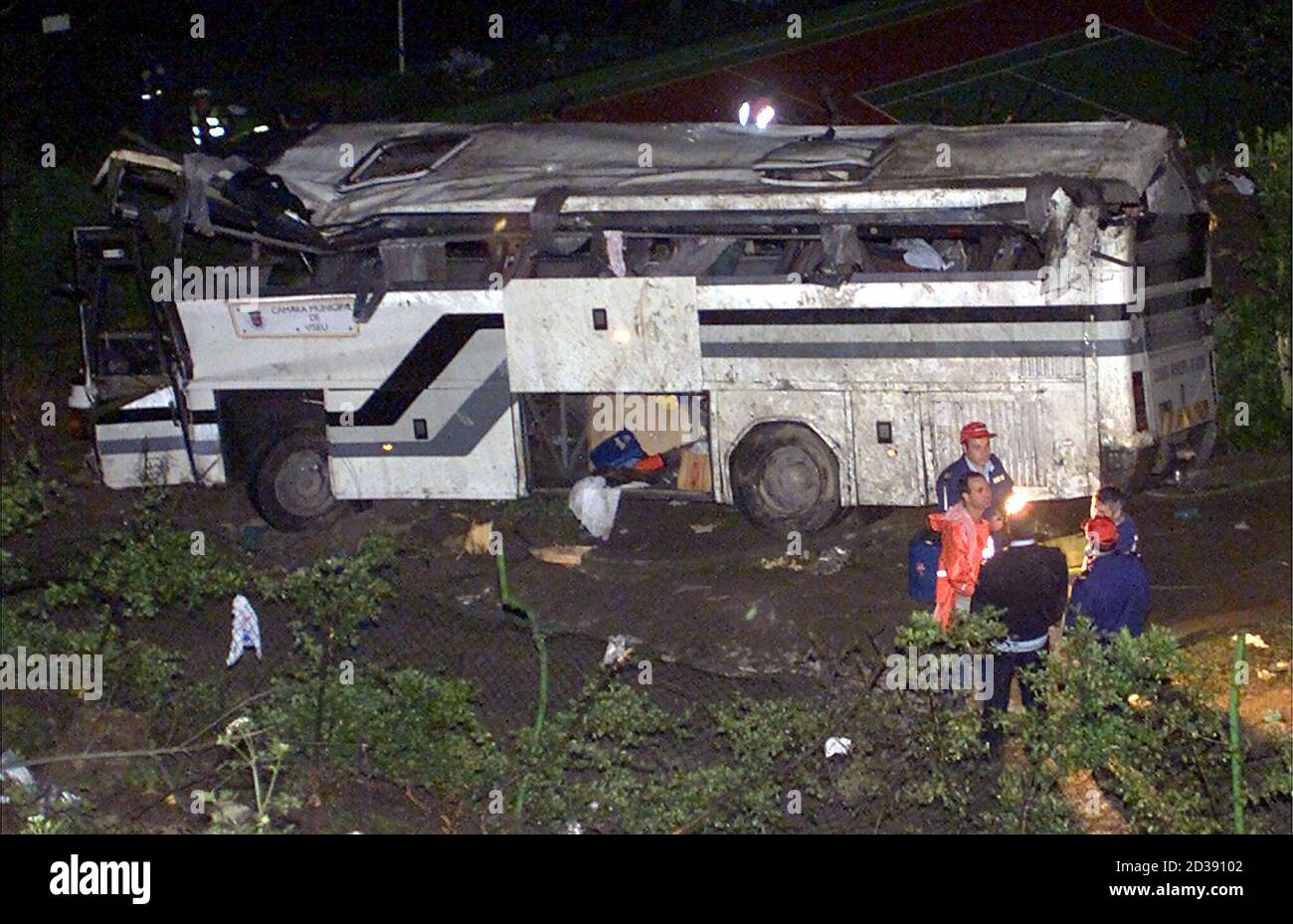 rescue workers stand in front of a crashed bus in central portugal 250 km from lisbon march 25 2001 at least 14 people were killed and 25 injured on saturday when a