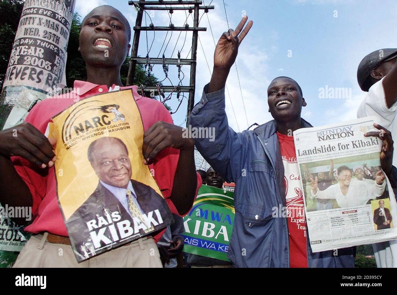 Celebrating supporters of NARC (National Rainbow Coalition) hold an  election poster of opposition leader Mwai Kibaki and a newspaper, with the  headline announcing Kibaki had won Kenya's presidential election, outside a  polling