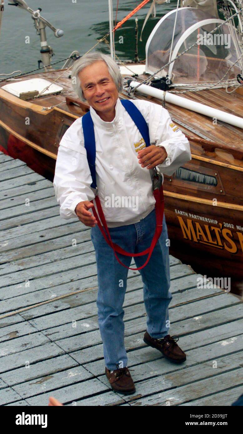 With his ship the 'Malt's Mermaid III' behind him, Japanese marine explorer Ken-ichi Horie smiles as he disembarks in San Francisco on July 17, 2002, at the end of his 67-day solo nonstop voyage across the Pacific Ocean from Japan. The voyage commemorates the 40th anniversary of Horie's original solo sail to San Francisco on his 19-foot long 'Mermaid' in 1962. REUTERS/Lou Dematteis  LD Stock Photo